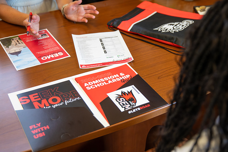 An open folder detailing admissions and scholarships for the 24-25 school year.