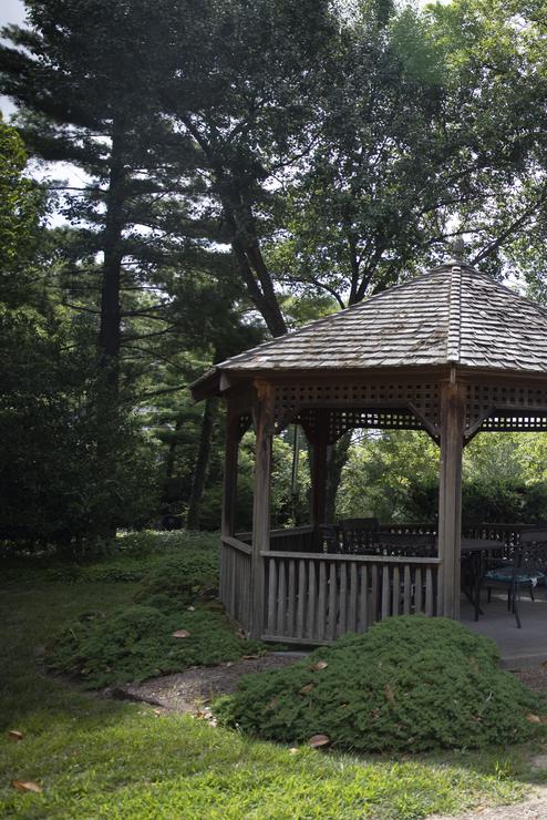A wooden gazebo sits on the property of the faculty center