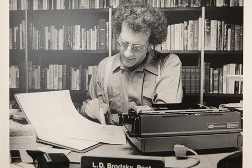 An old photo of Louis Daniel Brodsky looking at papers at a desk from a display in the Center for Faulkner Studies.