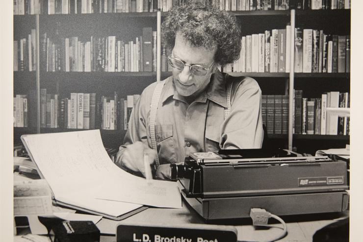 An old photo of Louis Daniel Brodsky looking at papers at a desk from a display in the Center for Faulkner Studies.