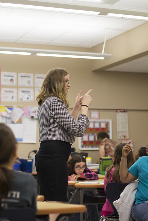 Lauren Harris gives instructions in the middle of a group of seated students.