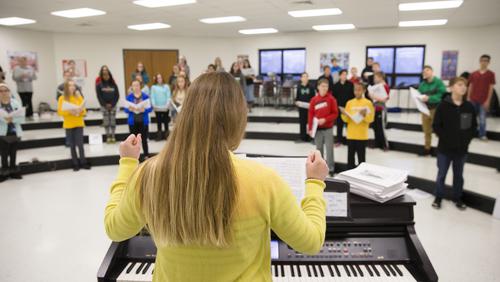 Danielle Jones, in a yellow sweater, leads a group of chorus students.