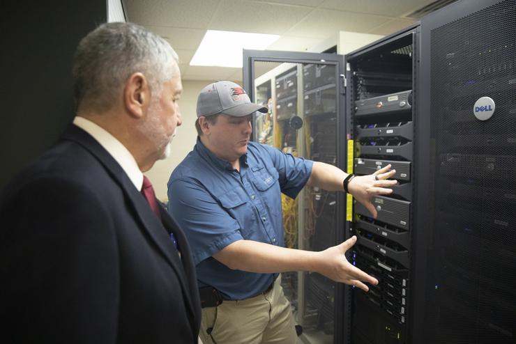 an information technology employee demonstrates the functions of a server to an onlooker