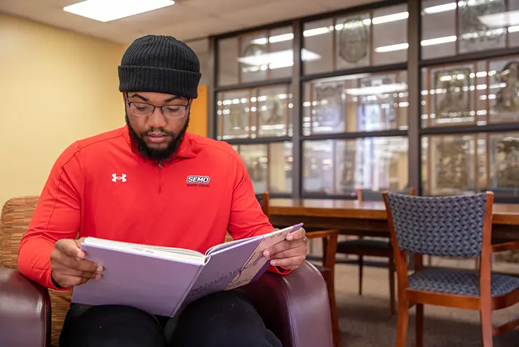 a semo student sits in kent library reading a book
