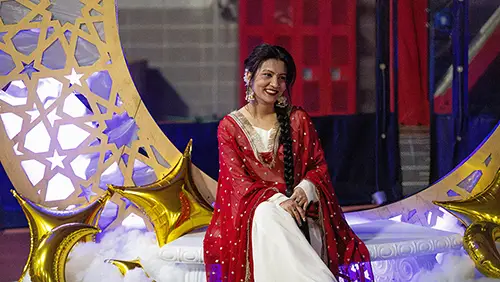 a member of the international community at SEMO wears her culturald dress and poses for a photo on a prop