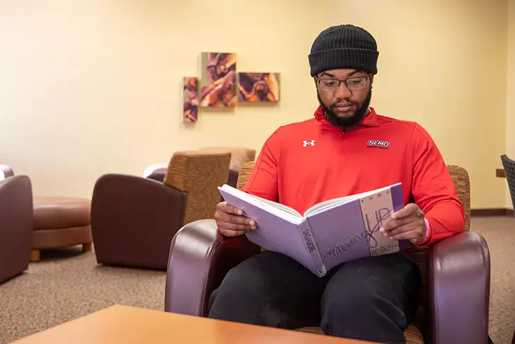 a SEMO student sits in kent Library and reads a book