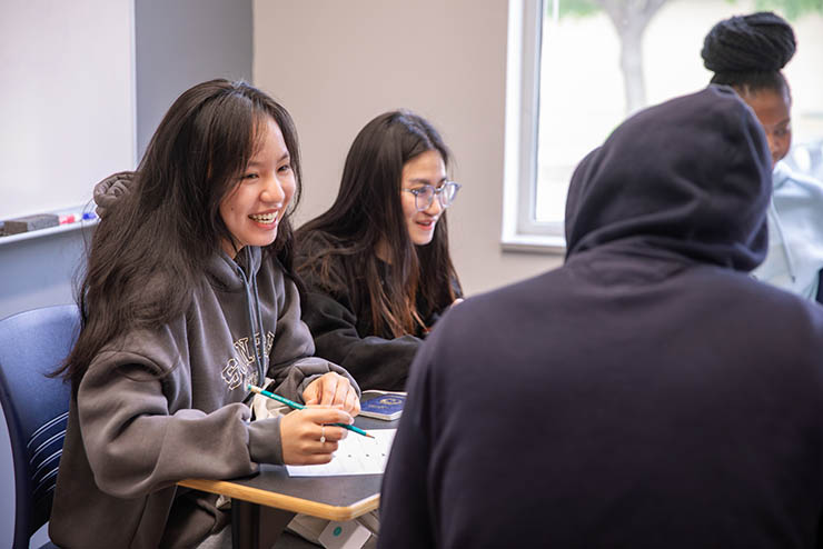 SEMO international students sit together at a table with papers in front of them, talking and smiling
