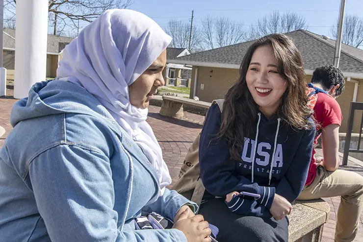 two international students at SEMO sit together on a bench and chat