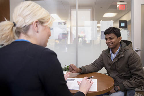 A SEMO international student is seated at a table with a SEMO staff member, talking