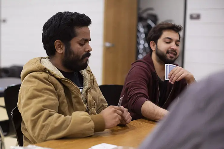 A group of SEMO international students sit around a table and play cards during a game night