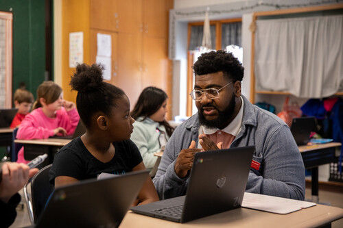 student teacher answering a students question in the classroom and giving her guidance on the assignement