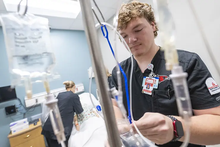 two SEMO nursing majors work with a practice mannequin in the nursing lab
