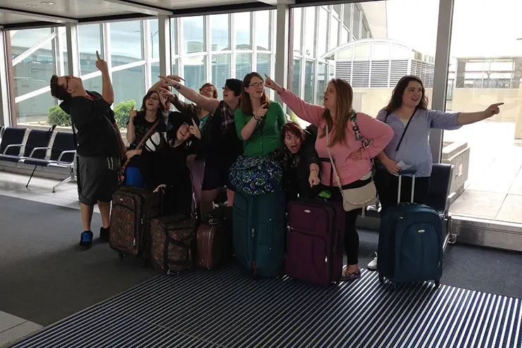 a group of SEMO students pose with their carry-on suitcases at the airport