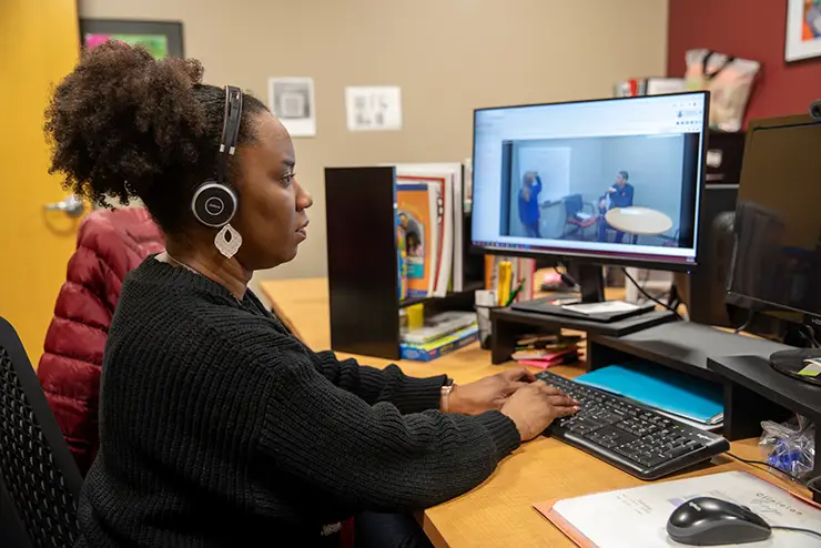 a SEMO student sits at a computer wearing a headset and participating in a communication disorders patient appointment