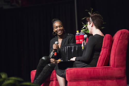 Public speakers seated in two red chairs on stage, engaging in a discussion at Southeast Missouri State University event.