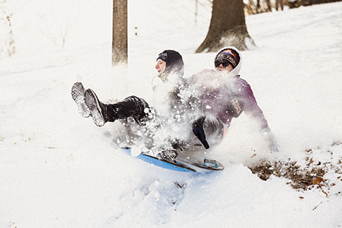 Two SEMO students collide while sledding sending snow flying.