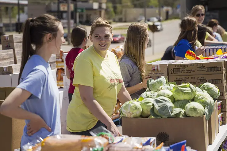 two semo students stand behind a table full of food for a food bank