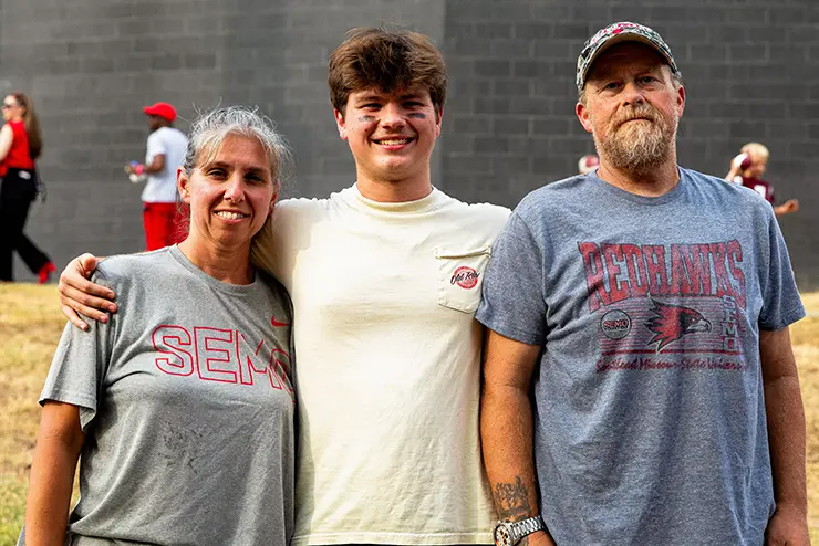 a student poses for a photo with his mom and dad during SEMO family weekend
