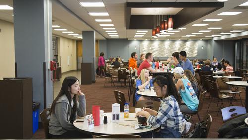 Numerous students sit at tables in a dining area of Redhawk Market.  