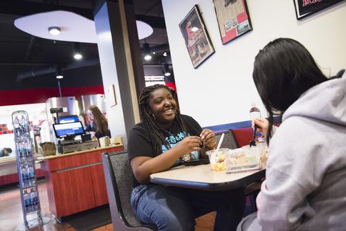 A student smiles while eating with a peer in a booth at Rowdy’s. 