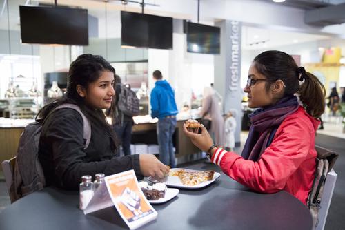 Students eat pizza at a table in Towers Café.