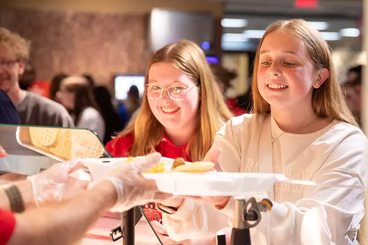 two SEMO students stand at a service counter and receive their meals
