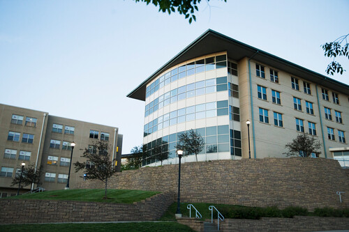 Sunlight reflects off the windows outside of Merick Hall with a blue sky in the background
