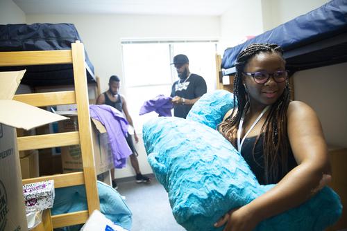 A student organizes her belongings in her new dorm room with the help of her family.