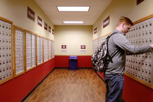 A semo student unlocks his mailbox at Towers Complex next to the customer service desk. 