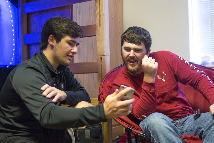 A Vandiver Hall residence shows his roommate a video on his phone while they lounge in their room.