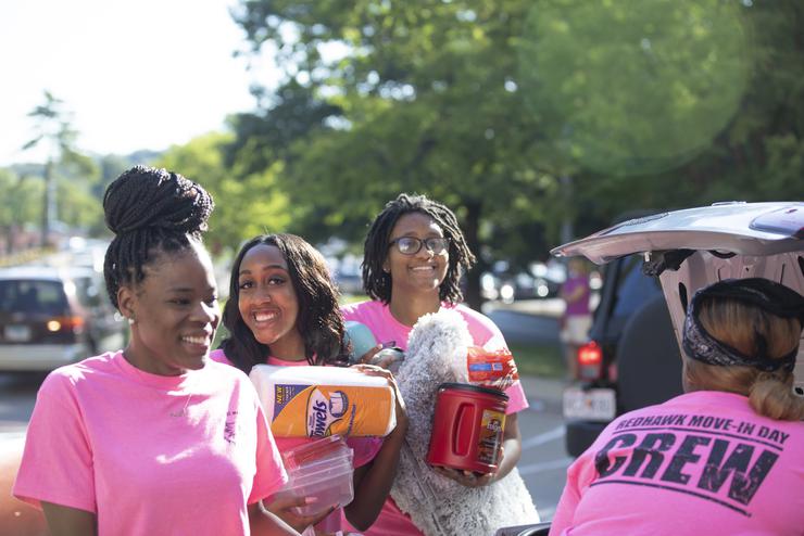 The move-in day crew helps carry a new student’s belongings from a car to their dorm room.