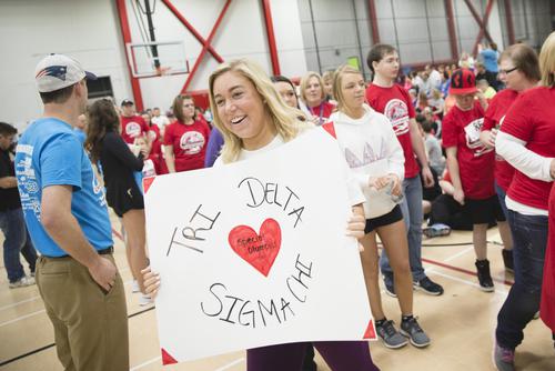 A smiling student holds a poster while volunteering at the Special Olympics.