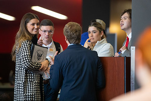 Several student government members stand around a podium talking.