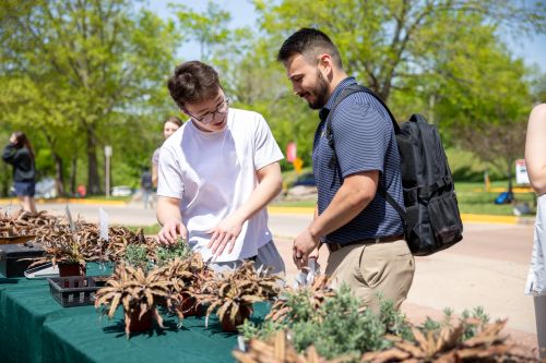 A semo student explains the plants on the table to another student during the Earth Day event.