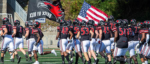 SEMO's football team runs onto Houck Field carrying both a SEMO and an American flag