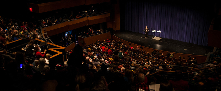 a full audience in the Bedell theatre with a student performing on stage