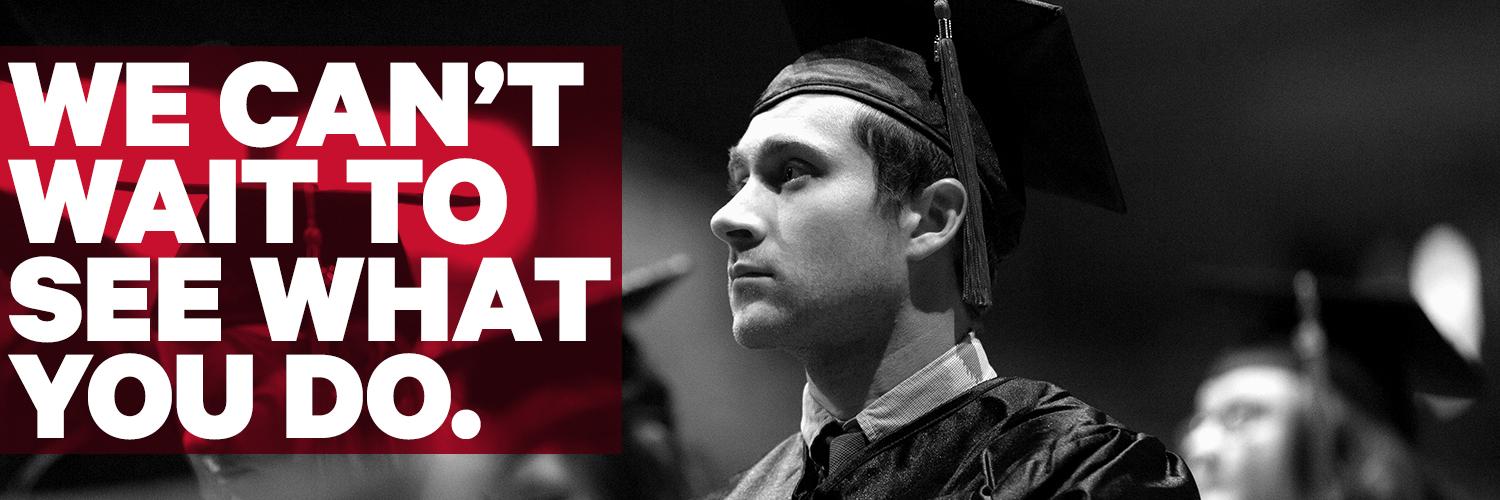 a student stands with his fellows wearing his cap and gown at commencement, text overlay of "We can't wait to see what you do."