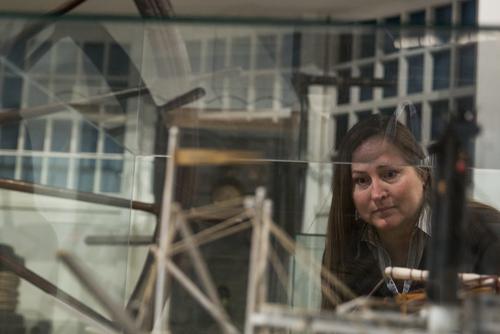 An individual bends down to view a riverboat model enclosed in a glass case.