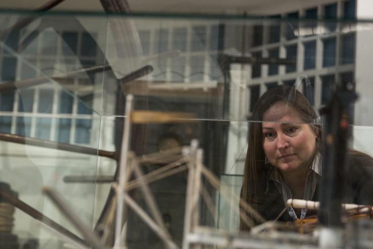 An individual bends down to view a riverboat model enclosed in a glass case. 