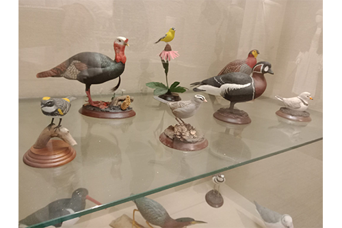 A picture of wood-carved birds, most notably a duck and turkey. All birds are realistic and painted.