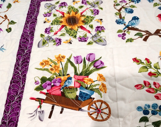 a quilt spread out to display wagons full of flowers in celebration of spring