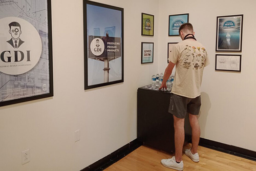Photo of a student standing in front of a display of posters adjusting something on a podium.