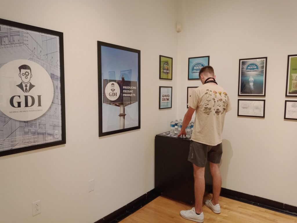 Student standing in front of a series of posters on the wall while adjusting something on a podium.