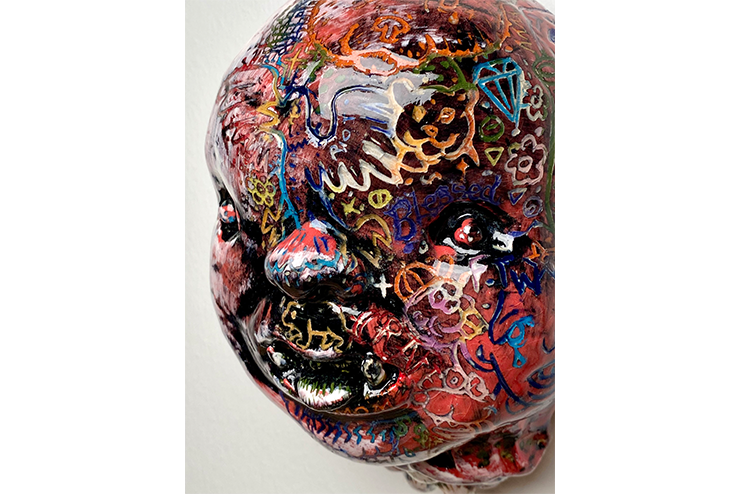 A ceramic baby face with drawings all over.