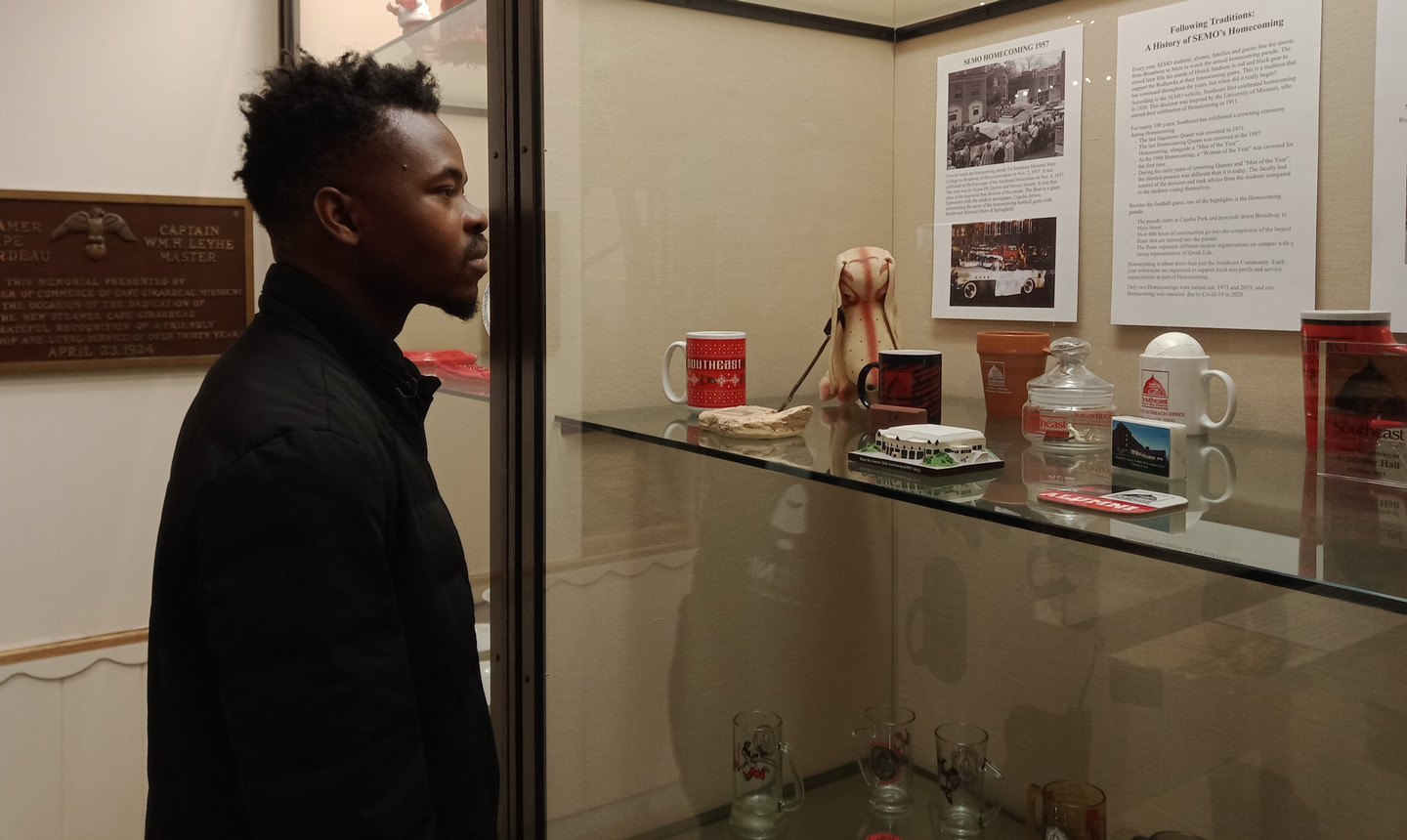 A young man is looking at semo artifacts inside a case.