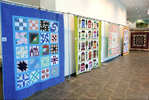 quilts hung up in rows in crisp museum