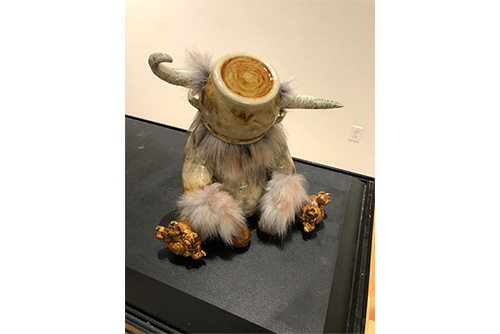 A statute of some kind of creature with a mug over its face.