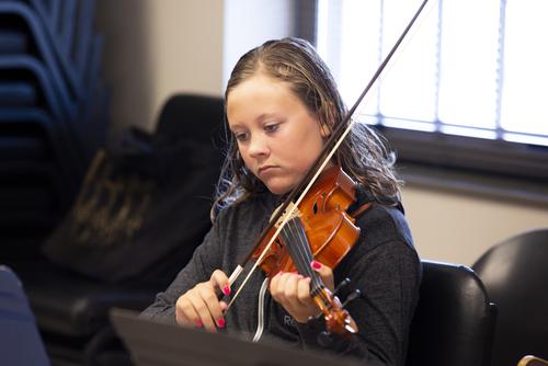 A Music Academy student practices playing the violin.