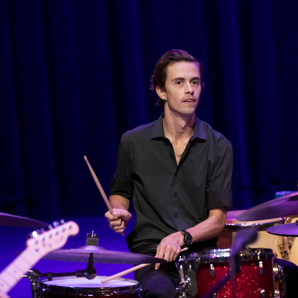 A student plays the drums during a performance. 