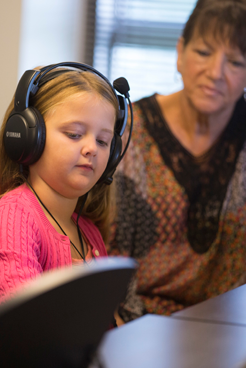 Little girl working with an instructor at the piano.